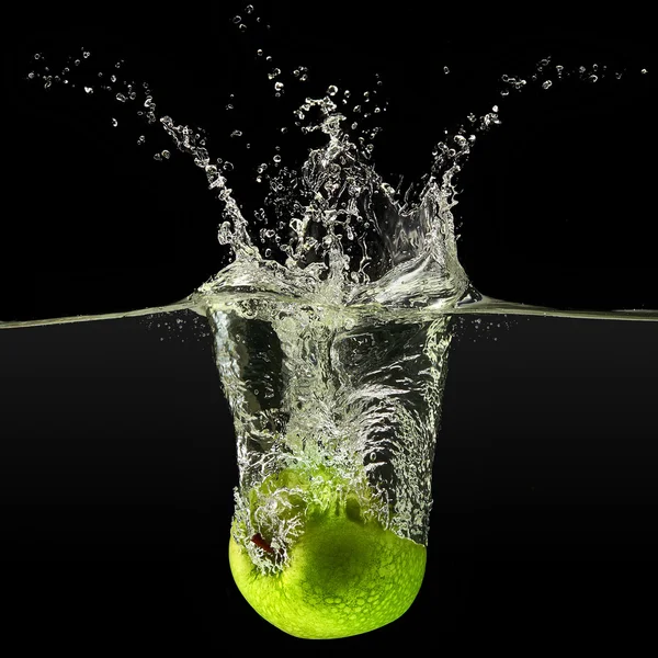 Green apple falling in water on black background — Stock Photo, Image