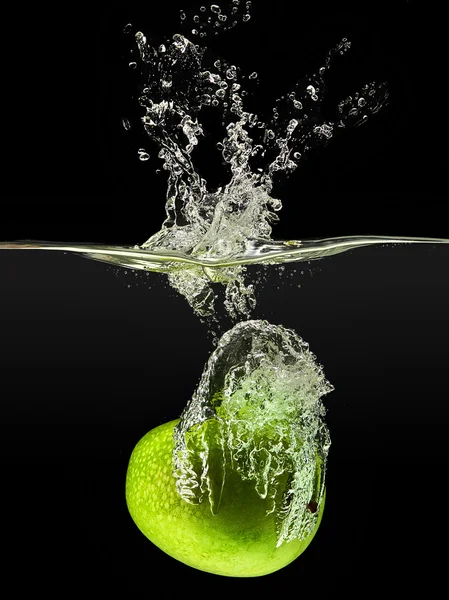 Mela verde che cade in acqua su sfondo nero — Foto Stock