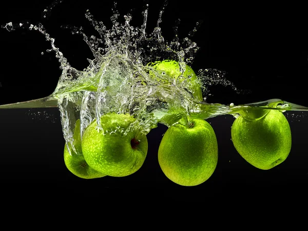 Gruppe grüner Äpfel fällt in Wasser auf schwarz — Stockfoto