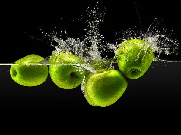 Grupo de manzanas verdes cayendo en el agua sobre negro — Foto de Stock