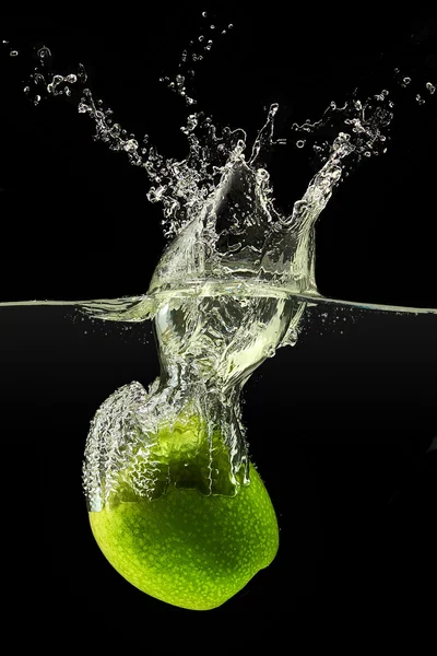 Grüner Apfel fällt ins Wasser auf schwarzem Hintergrund — Stockfoto