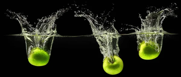 Mela verde che cade in acqua su sfondo nero — Foto Stock