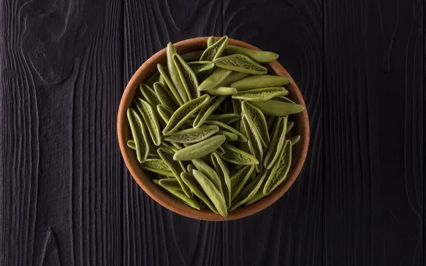 Top view of foglie spinach pasta in bowl on black wooden table — Stock Photo, Image