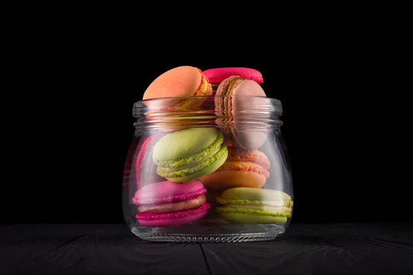 Frasco de macaroon colorido francês ou macaron na mesa de madeira isolada em preto — Fotografia de Stock