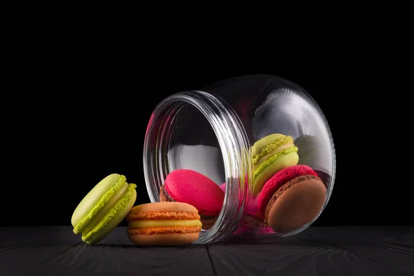 Jar of french colorful macaroon or macaron on wooden table isolated on black — Stock Photo, Image