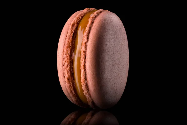 Macro photo de macaron caramel français avec réflexion isolée sur noir . — Photo