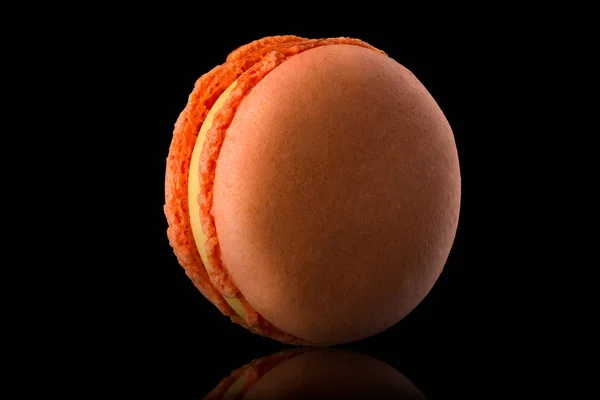 Macro foto di macaron rosa arancio francese con riflesso isolato sul nero — Foto Stock