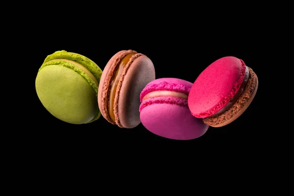 Voando macaroons coloridos franceses na mesa de madeira isolada no preto — Fotografia de Stock