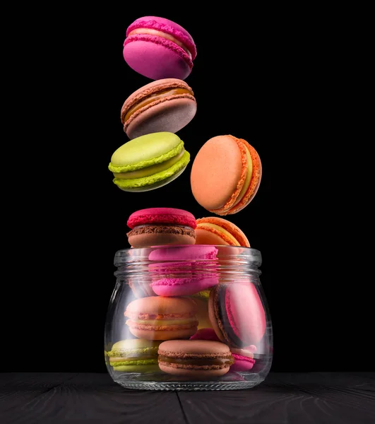 Jar of french colorful macaroons on wooden table isolated on black — Stock Photo, Image