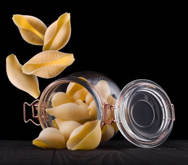 Siyah arka planda izole edilmiş ahşap masa üzerinde koni makarna kavanozu