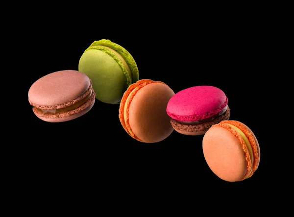 Voando macaroons coloridos franceses na mesa de madeira isolada no preto — Fotografia de Stock