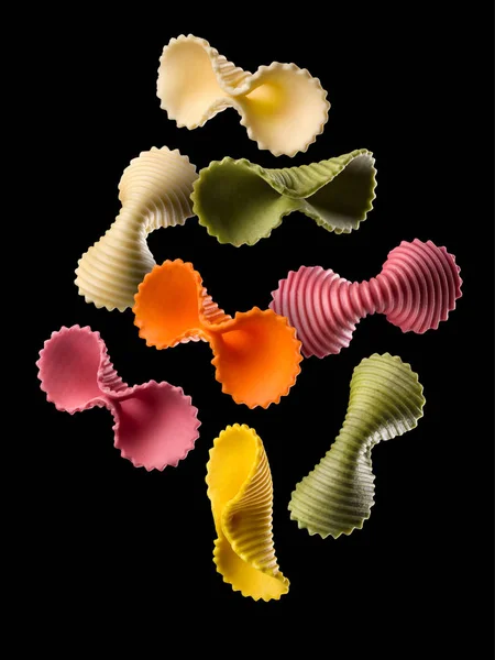 Macarrão farfalle colorido voador isolado em fundo preto — Fotografia de Stock