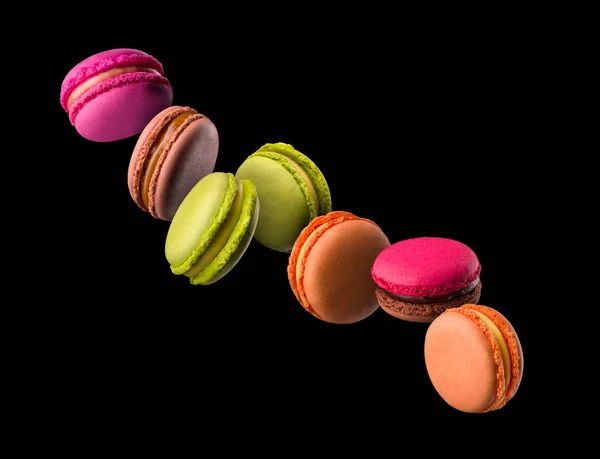 Voando macaroons coloridos franceses na mesa de madeira isolada no preto — Fotografia de Stock