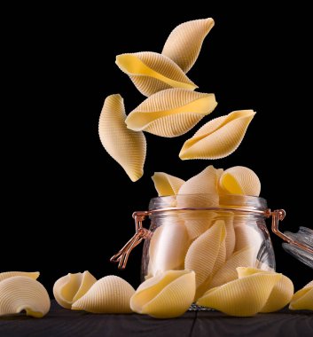 Siyah arka planda izole edilmiş ahşap masa üzerinde koni makarna kavanozu