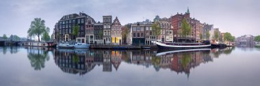 Suyun üzerindeki binaların yansımasıyla Amsterdam şehri manzarası
