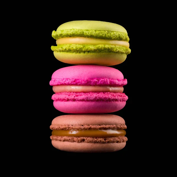 Fila de macaroons coloridos franceses ou montão na mesa de madeira isolada em preto — Fotografia de Stock