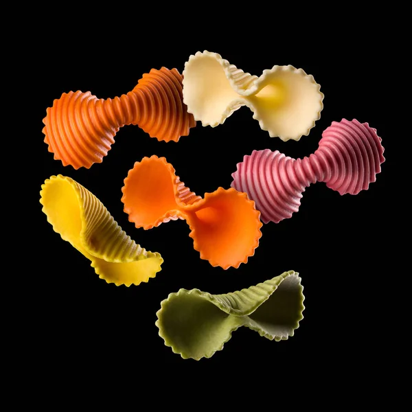 Vliegende kleurrijke farfalle pasta geïsoleerd op zwarte achtergrond — Stockfoto