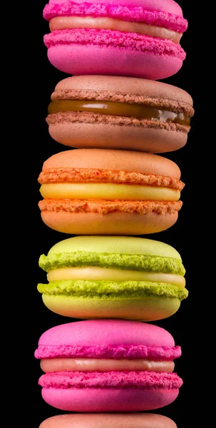 Empilement de macarons colorés français sur table en bois isolé sur fond noir — Photo