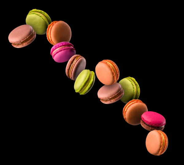 Macaron volanti colorati francesi su tavolo di legno isolato su nero — Foto Stock