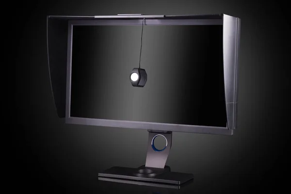 Monitor profissional com capa de sombreamento e calibrador isolado em preto — Fotografia de Stock