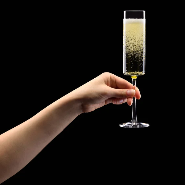 Donna mano che tiene il bicchiere di champagne frizzante isolato su nero . — Foto Stock