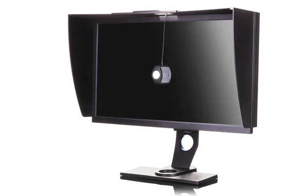 Monitor profissional com capa de sombreamento e calibrador isolado em branco — Fotografia de Stock