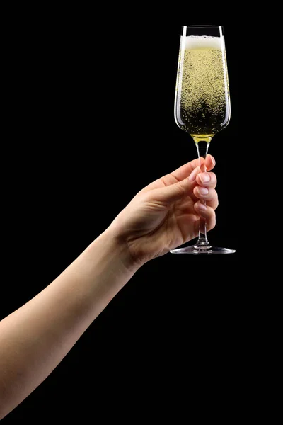 Donna mano che tiene il bicchiere di champagne frizzante isolato su nero . — Foto Stock