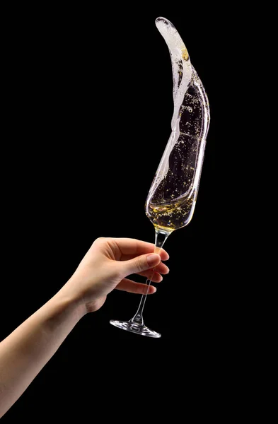 Woman hand holding glass of sparkling champagne with splashes isolated on black. — Stock Photo, Image