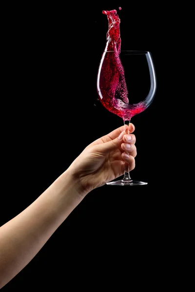 Vrouw hand met rode wijn glas met spatten geïsoleerd op zwart. — Stockfoto
