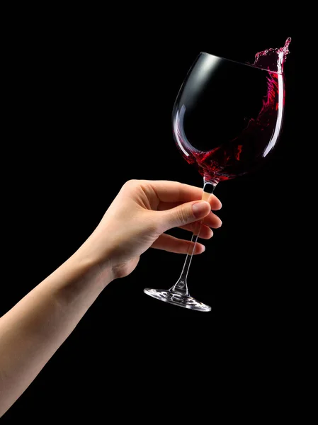 Woman hand holding red wine glass with splashes isolated on black. — Stock Photo, Image