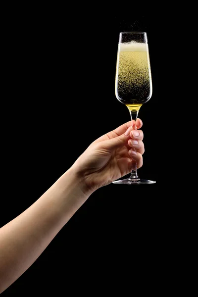 Woman hand holding glass of sparkling champagne isolated on black. — Stockfoto