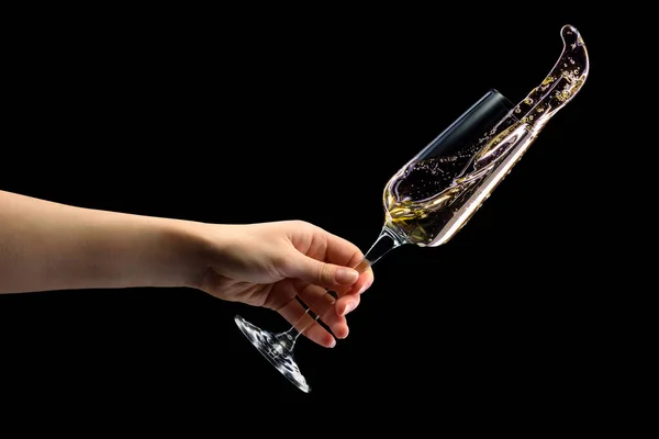 Ręka kobiety trzymającej szklankę musującego szampana z odizolowanymi na czarno rozpryskami. — Zdjęcie stockowe