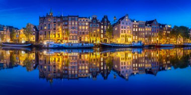 Amsterdam 'ın gece manzarası, sudaki binaların yansımasıyla