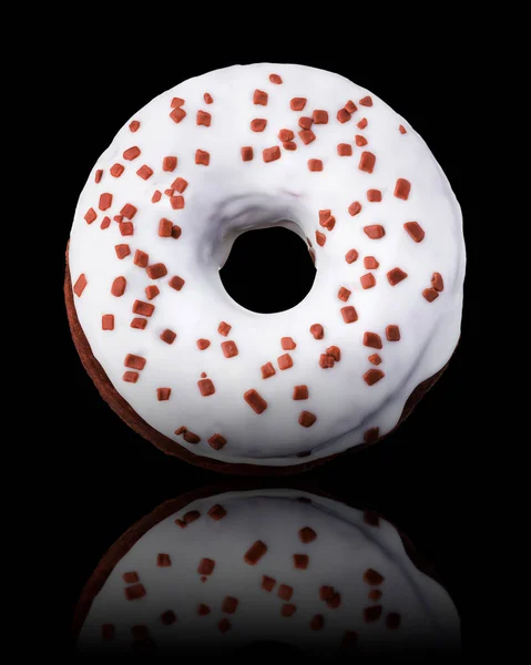 Glasierter Donut mit Streusel auf schwarzem Hintergrund, gedreht in drei Vierteln — Stockfoto