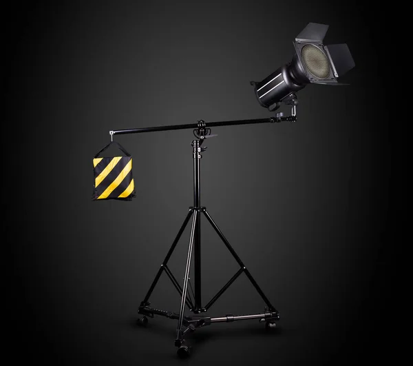 Photography studio flash on a lighting stand isolated on black background with lamp. Proffetional equipment like monobloc or monolight