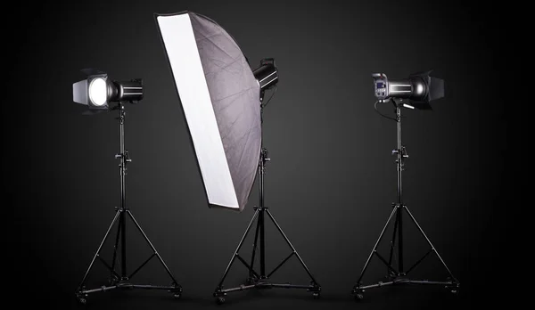 Stojaki oświetleniowe studio fotograficzne z lampą błyskową i softbox izolowane na czarno. — Zdjęcie stockowe