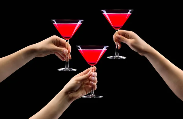 Set of hands holding strawberry martini glass isolated on black.