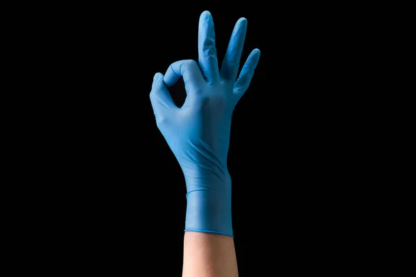 Doctors hand in sterile medical gloves in gesture of okay isolated on black — Stock Photo, Image