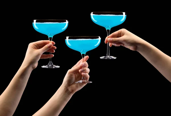 Ein Satz Hände, die ein Glas Sekt mit blauem Sekt halten, isoliert auf schwarz. — Stockfoto