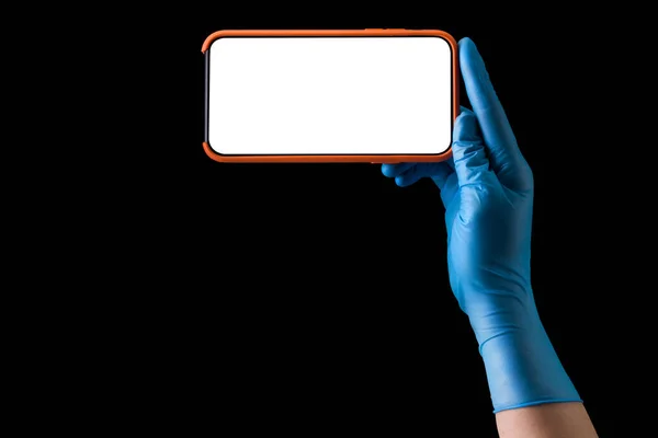 Doctors hand in medical gloves holding phone isolated on black — Stock Photo, Image