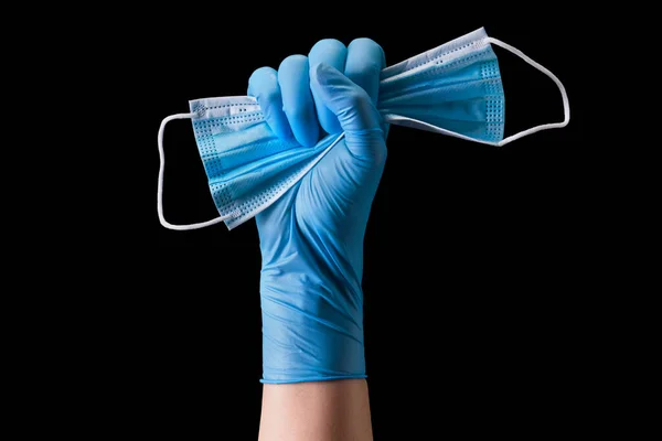 Doctor\'s hand in medical gloves holding a mask isolated on black background with clipping path. Concept of protection against pandemic and viruses.
