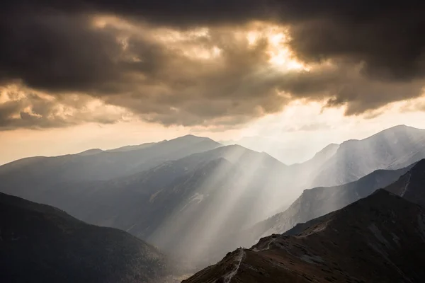 Sunlight beaming through clouds above Tatra mountains in Poland
