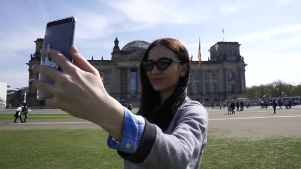 Fiatal, mosolygós nő Self Portrait Smartphone Reichstag épülete Berlin közelről — Stock videók