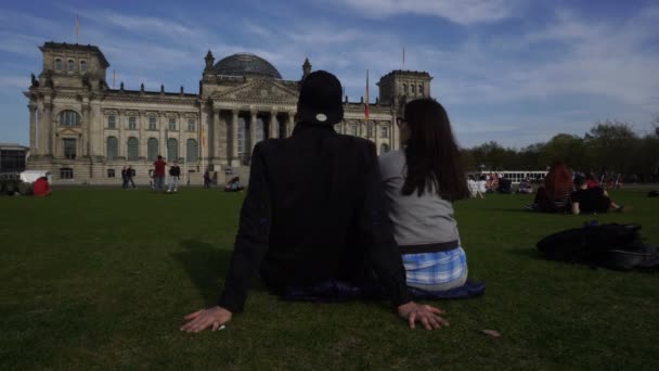 国会議事堂、ベルリン、ドイツの草原のカップルします。 — ストック動画