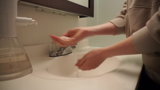 Femme se laver les mains avec de l'eau de savon liquide dans l'évier de salle de bain — Video