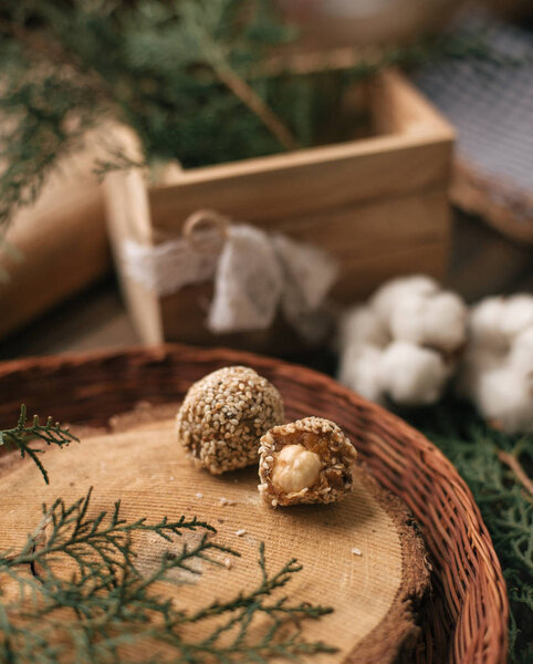 Decorative composition with chocolate candies on cross section of tree in wicker plate and coniferous twig.