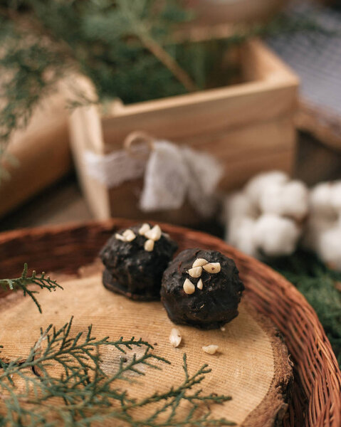 Decorative composition with chocolate candies on cross section of tree in wicker plate and coniferous twig.