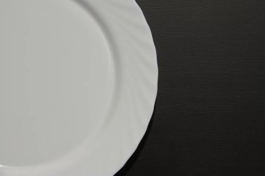 Siyah zemin üzerinde beyaz halka plaka, çanağın yarısı mat masasında boş, metin için boş yer 