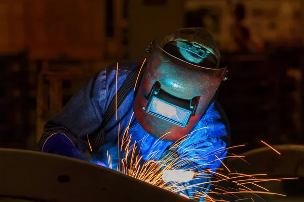 Industrial worker is welding assembly part in car factory