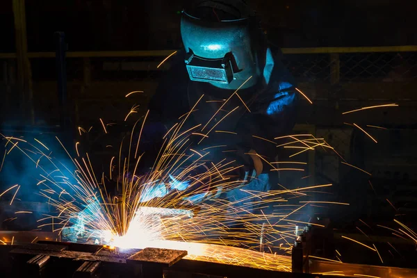 Industrial worker is welding in automotive part factory